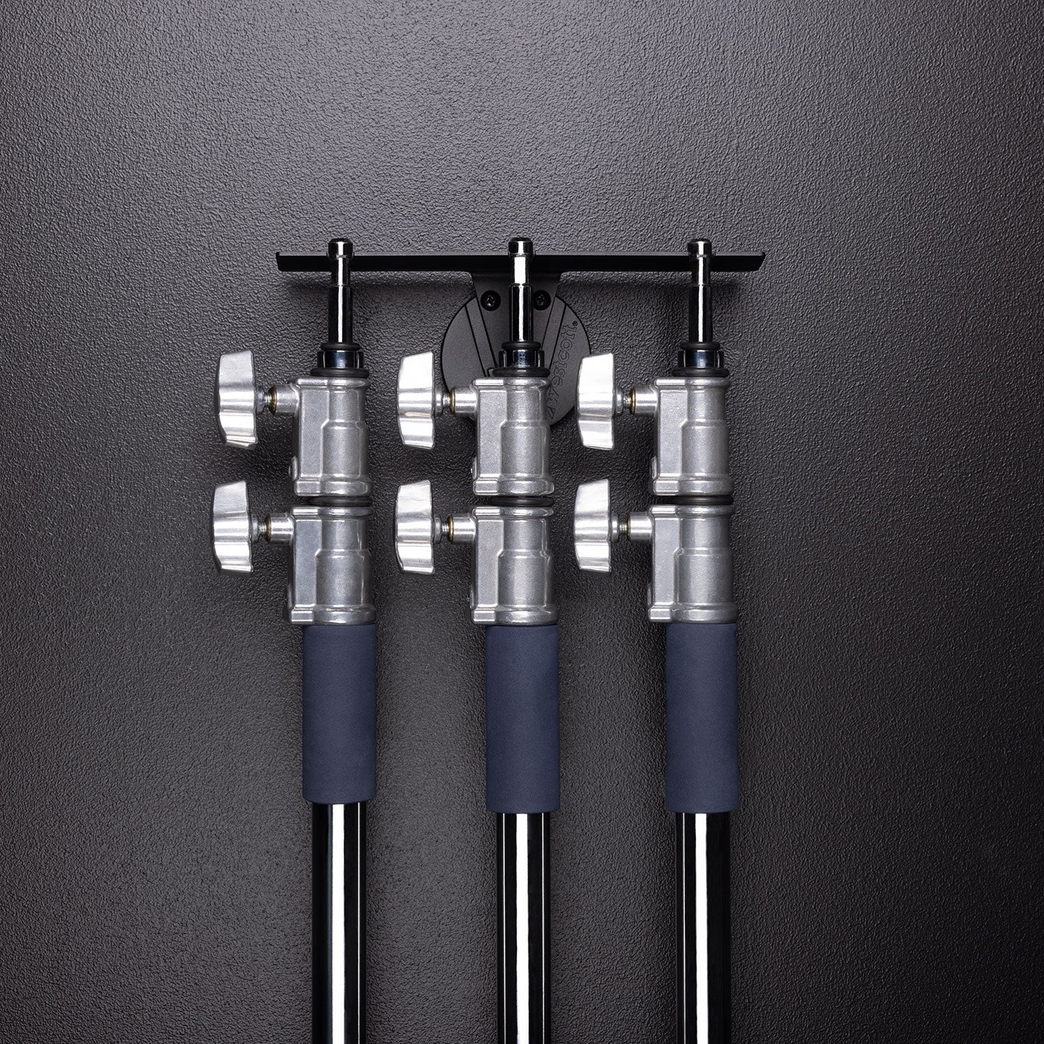 Float Wall Mount Light Stand Hanger shown with large light stands in storage
